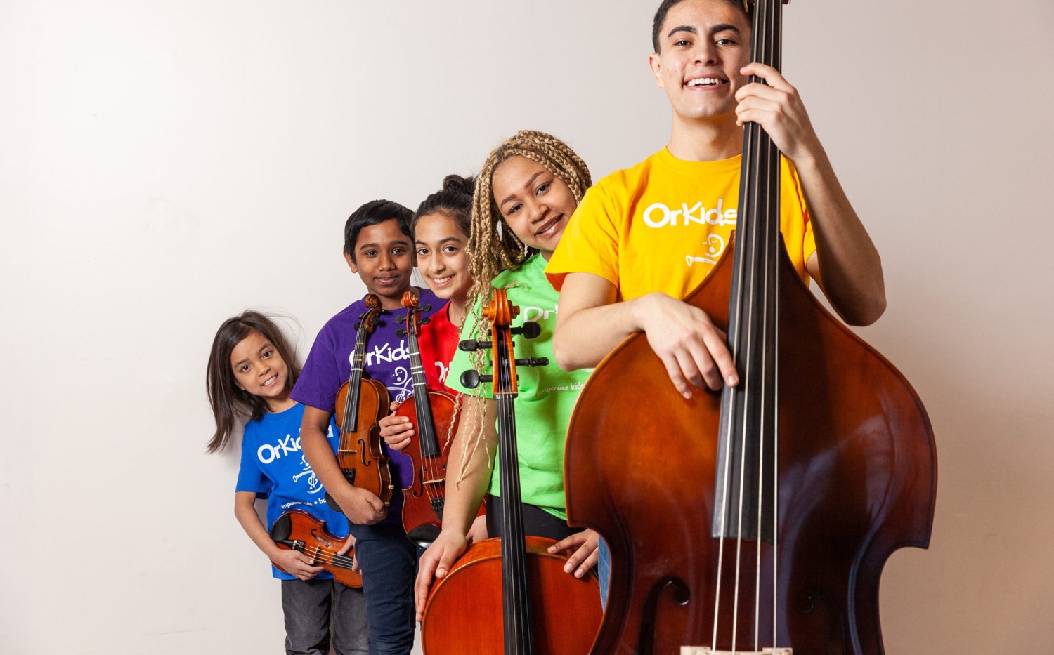 Young OrKidstra musicians with violins, a cello and a double bass